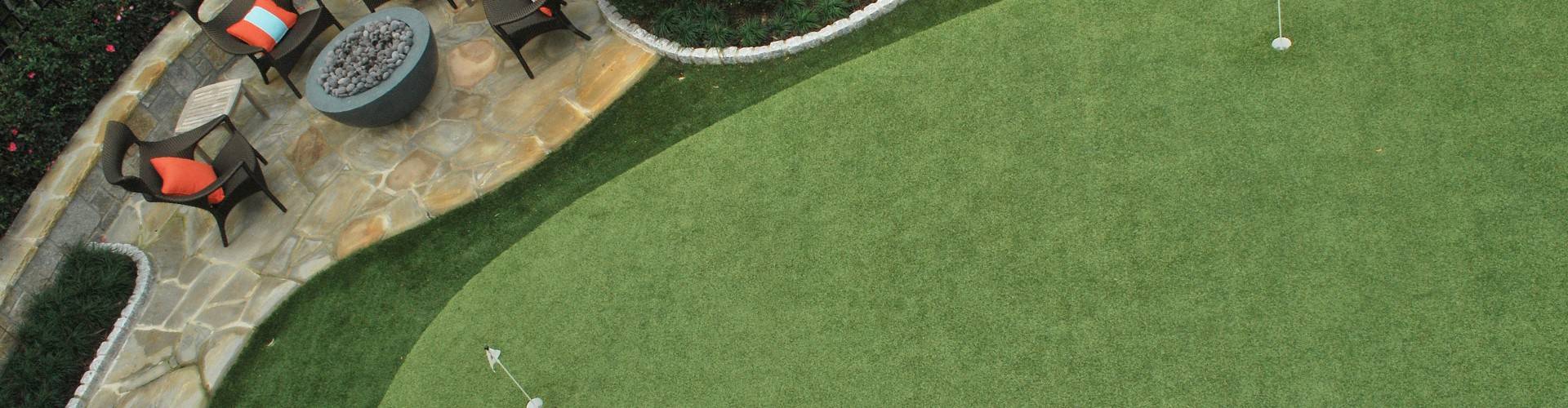 Custom backyard putting green with two holes and adjacent flagstone patio with fire pit and lounge seating